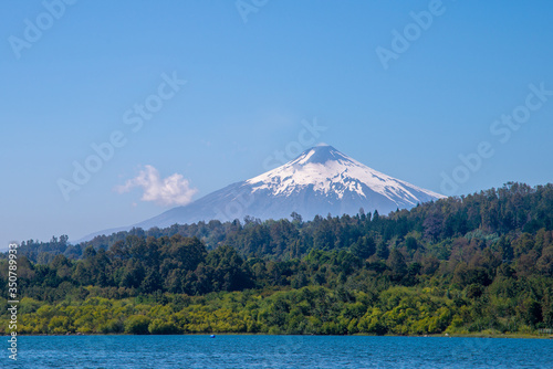 Villarrica volcano with a snow-capped peak against a blue sky. View from Villarrica Lake in the Pucon town. Chile © Liusia