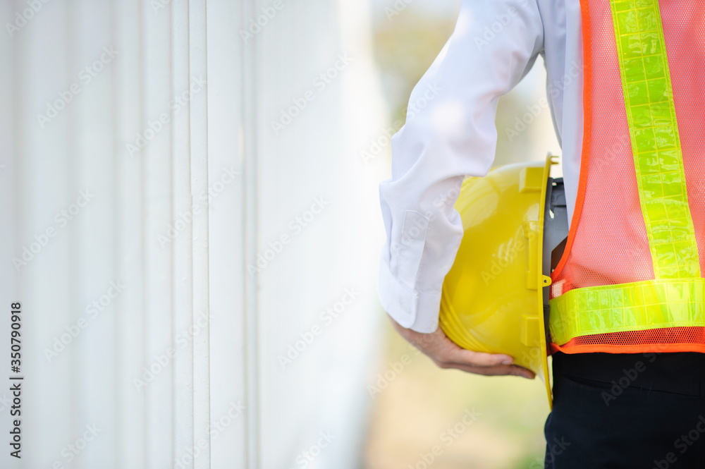 Engineer holding yellow helmet safety hard hat construction background Engineer holding yellow helmet safety hard hat construction background