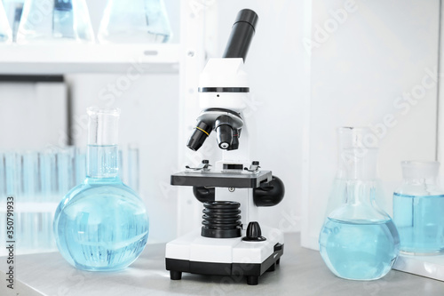 Modern microscope and glassware on table in laboratory