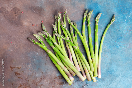 Freshly picked raw organic green asparagus spears for cooking healthy vegetarian food on a dark concrete background.