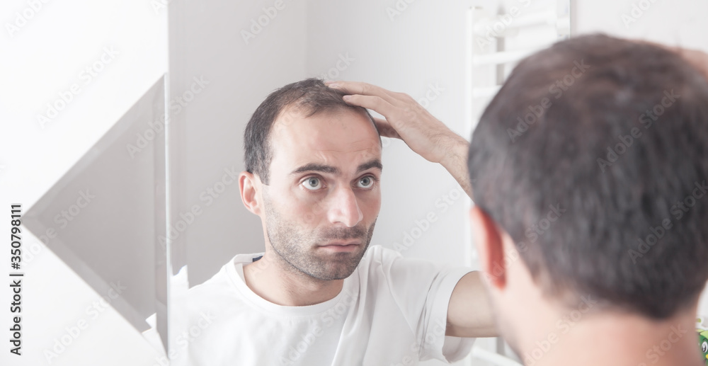 Fototapeta premium Caucasian man looking hair near mirror. Hair loss