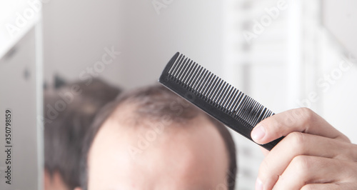 Caucasian man holding comb in bathroom.