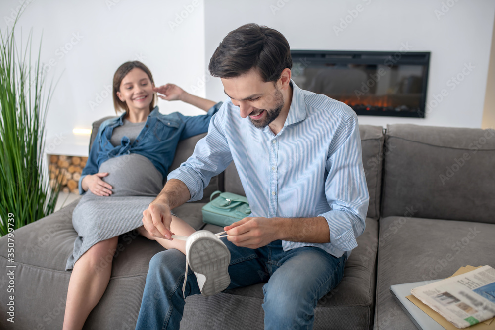 Dark-haired man taking off his wifes sneakers, woman smiling Dark-haired man taking off his wifes sneakers, woman smiling