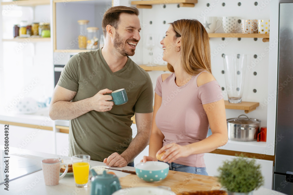 Young couple making breakfast at home. Loving couple drinking coffee in kitchen.
