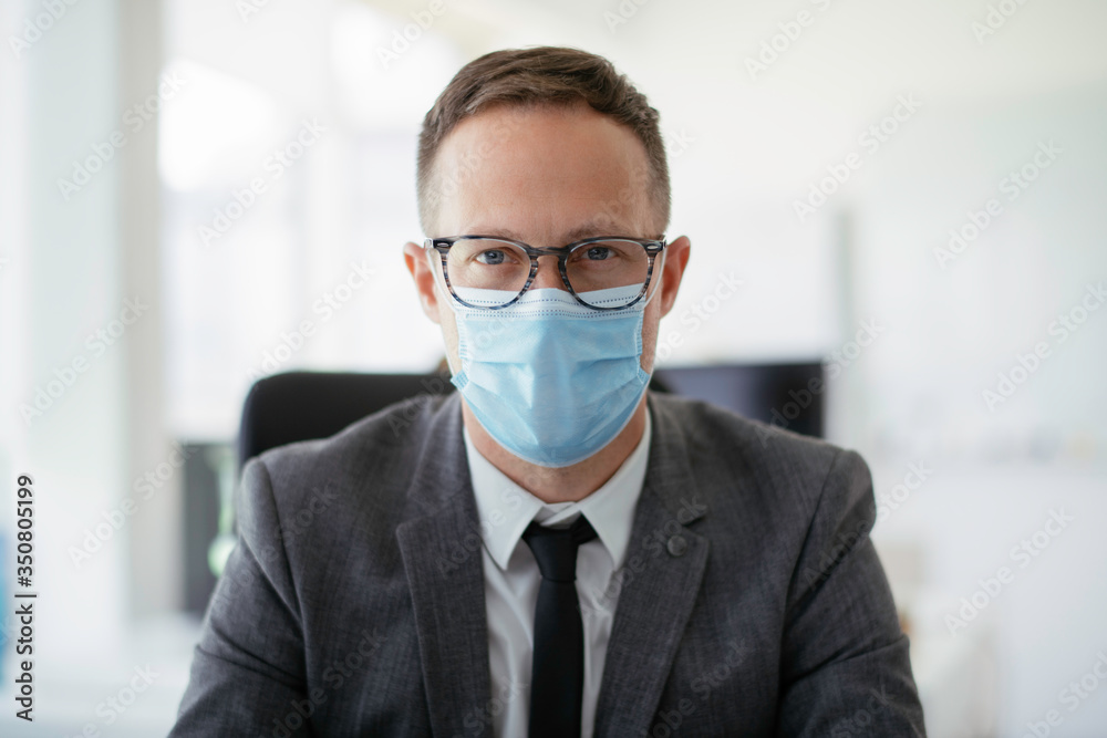 Handsome businessman with medical mask. Young businessman working in office.