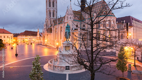 Catholic Matthias Church and Statue of Saint Stephen on Fishermans Bastion in Budapest, Hungary on sunrise with light from lanterns