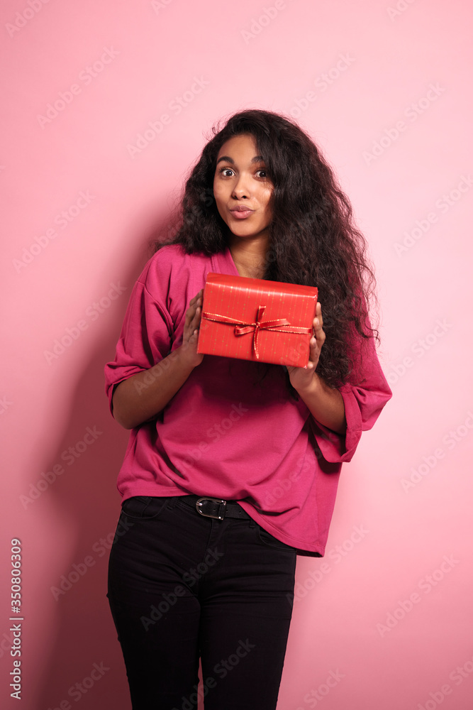 Young African woman holding red present in studio shot. Young African woman holding red present in studio shot.
