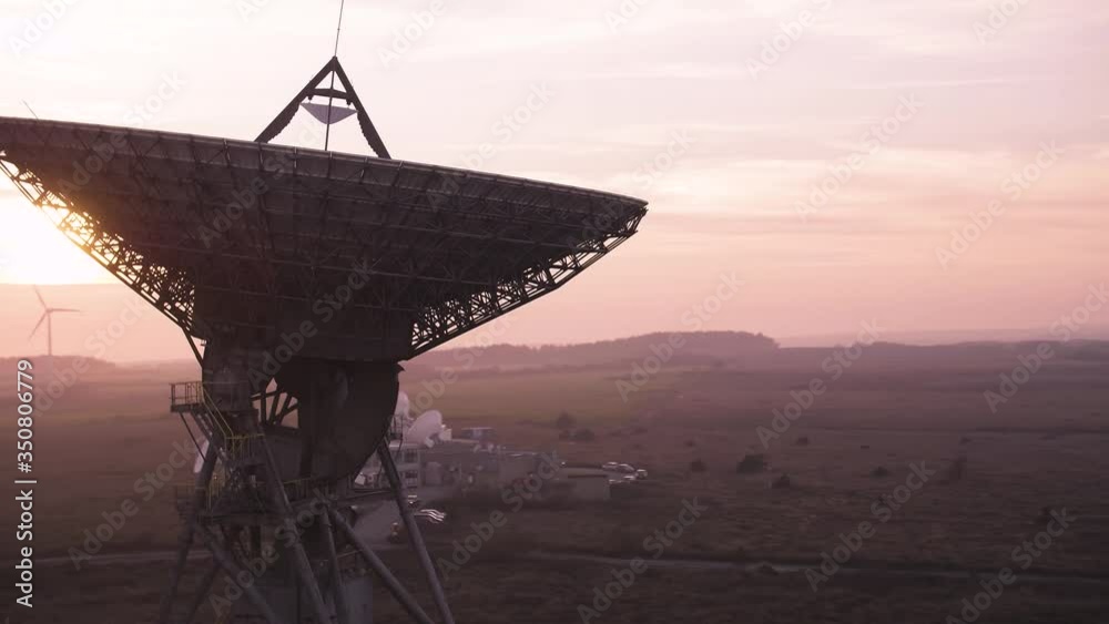 Cinematic aerial of a massive satellite dish searching space for new discoveries. Purple moody dusk environment Cinematic aerial of a massive satellite dish searching space for new discoveries. Purple moody dusk environment