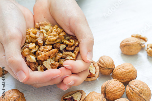 Organic walnuts in the hands on wooden background