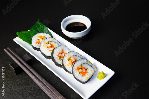 Sushi roll set serving on white plate over black table background - favorite dish Japanese food concept