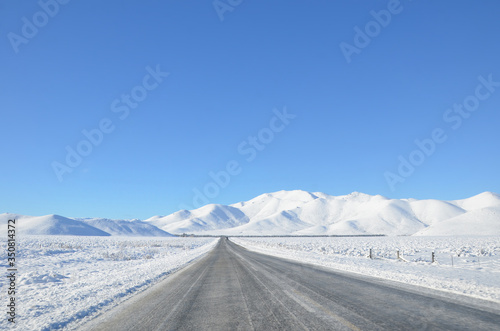 The winter snowy road from Lake Tekapo to Christchurch. The journey pass through several towns and along farmland, then the scenery will start to become mountainous. photo