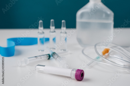 Health care medical products for the treatment of illness, viruses and infections. Test tube for taking biolosic material blood with a label pouring on the table on a blue background.