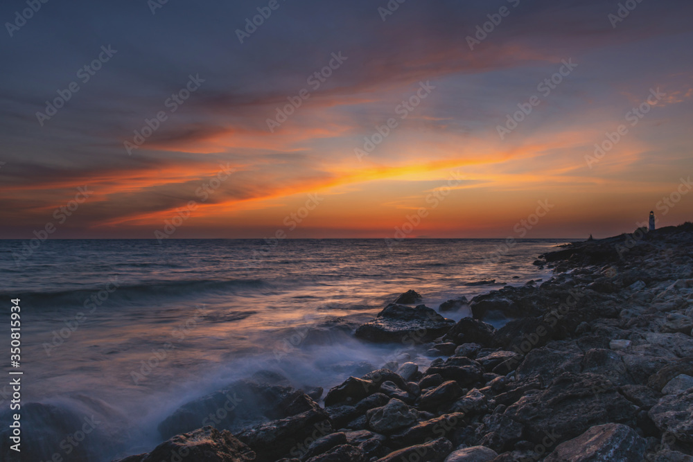 The sea coast at sunset with beautiful clouds. The blurred movement of water using long exposure. Dreams of summer. Magnificent cloud landscape. The fiery sky with the setting sun.