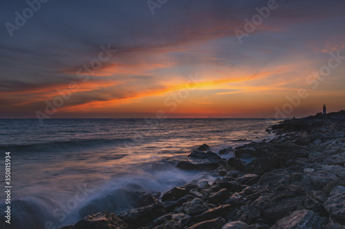 The sea coast at sunset with beautiful clouds. The blurred movement of water using long exposure. Dreams of summer. Magnificent cloud landscape. The fiery sky with the setting sun.