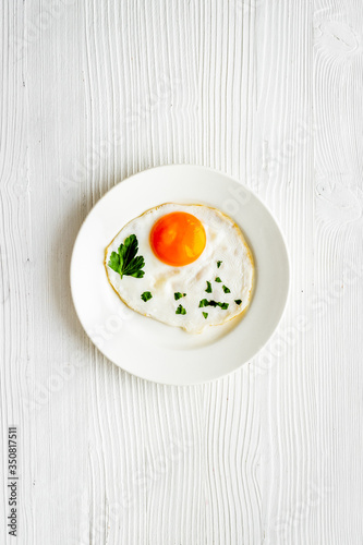 Fried eggs on plate - white wooden kitchen table top-down