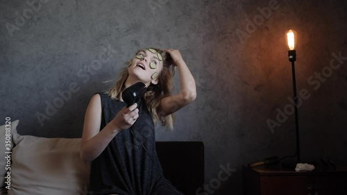 The woman dries the hair dryer with fooling around and sing into your hairbrush