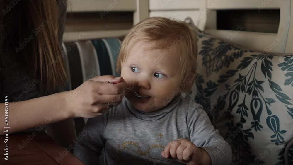 Mother feeding little girl mashed with a spoon close-up Mother feeding little girl mashed with a spoon close-up