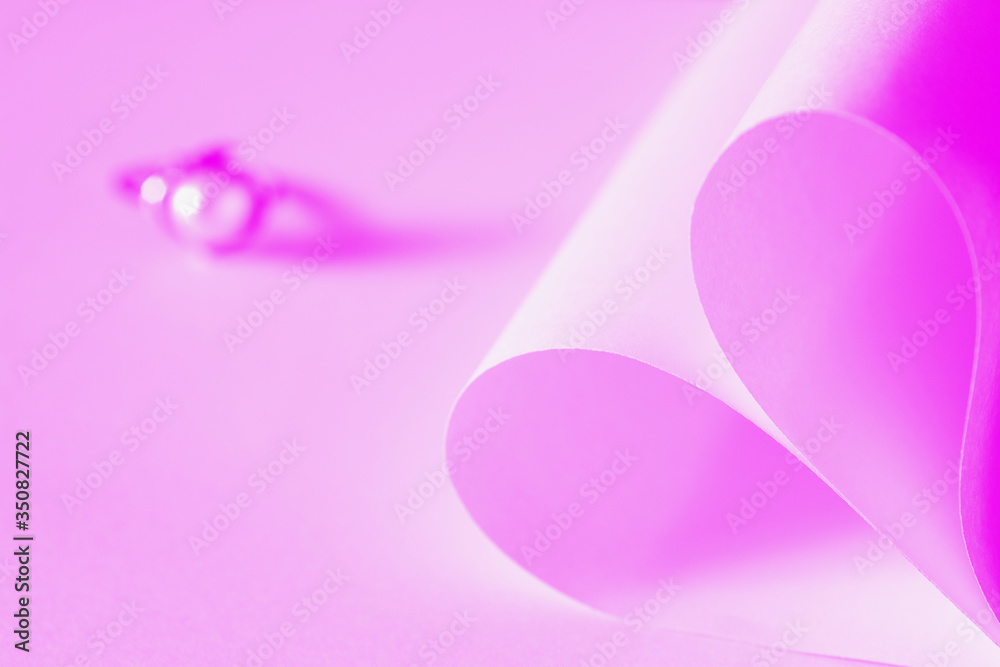 Heart shaped origami paper and pearl ring on pink background. Heart shaped origami paper and pearl ring on pink background.