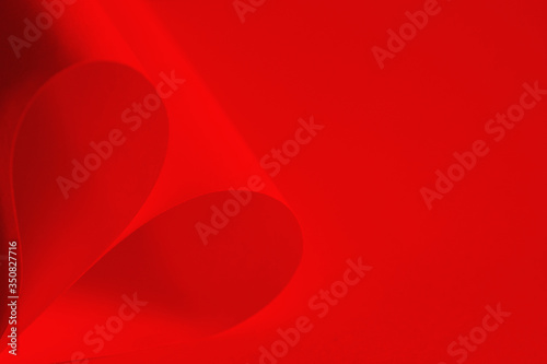 Red heart shaped origami paper on red background.