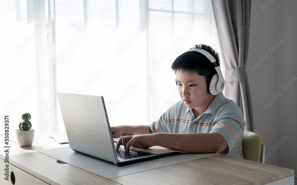 Asian Kid self isolation using laptop for his homework, Social Distance, E-learning online education. Asian Kid self isolation using laptop for his homework, Social Distance, E-learning online education.