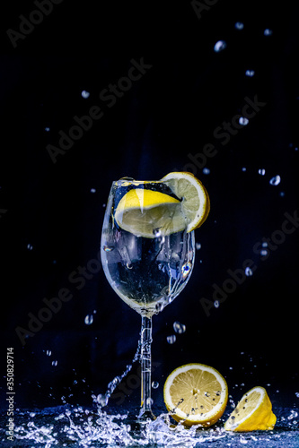 a lemon splashing in a glass of alchohol