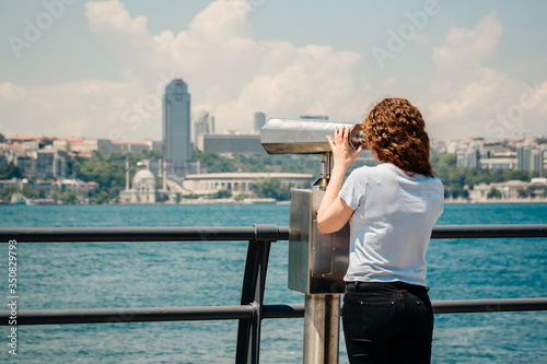 young woman looking at the city, girl looks through tourist binoculars on the old city of Istanbul, Bosphorus, Turkey