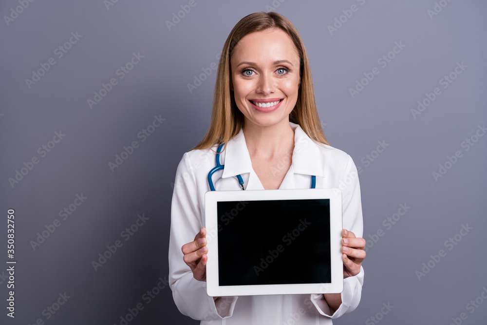 Close-up portrait of nice attractive content cheerful blonde girl doc therapist showing medical web service device wireless connection isolated over grey violet pastel color background Close-up portrait of nice attractive content cheerful blonde girl doc therapist showing medical web service device wireless connection isolated over grey violet pastel color background