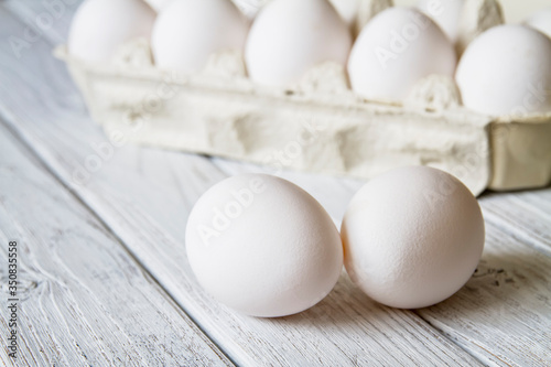 Close-up of fresh white organic chicken eggs in the paper tray on light wooden background