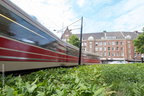 A moving tram at day, houses in background, blue sky, in long exposure. The Hague, the Netherlands