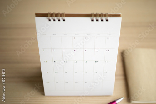 calendar page close up on wood table background with pen and notebook business planning appointment meeting concept