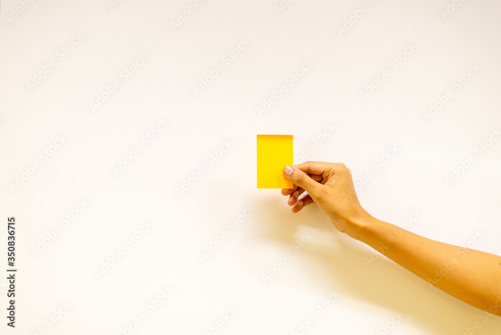 A person is attaching yellow paper to a white board.