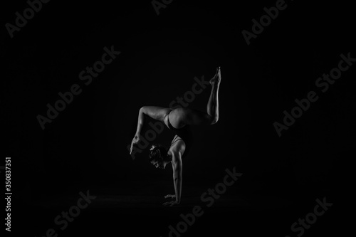 Girl yogi performs exercises on a black background. The flexibility of the female body. Asana. Relief of the muscles. Figures from the body.