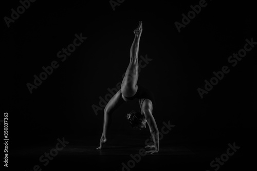 Girl yogi performs exercises on a black background. The flexibility of the female body. Asana. Relief of the muscles. Figures from the body. © Dima