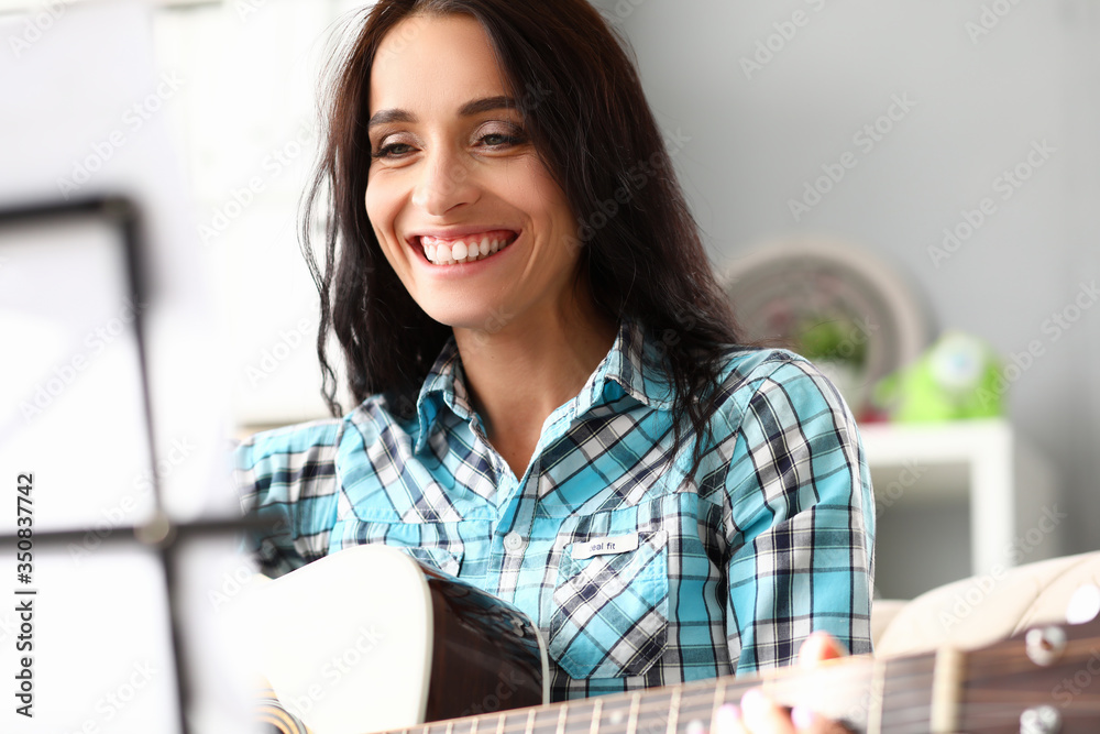 Beautiful woman plays guitar at home and laughs