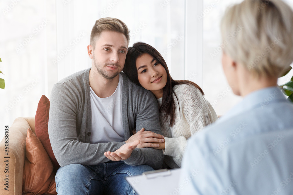 Loving Couple Embracing After Session With Psychologist Sitting In Office Loving Couple Embracing After Session With Psychologist Sitting In Office