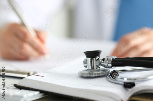 Stethoscope head lying on medical forms closeup