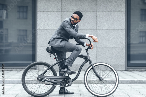 Handsome afro businessman riding his bike to work