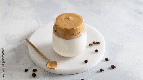 Homemade Dalgona coffee in glass with coffee beans on white table. Recipe popular Korean drink latte with foam of instant coffee. Created new drink during Quarantine and self-isolation.