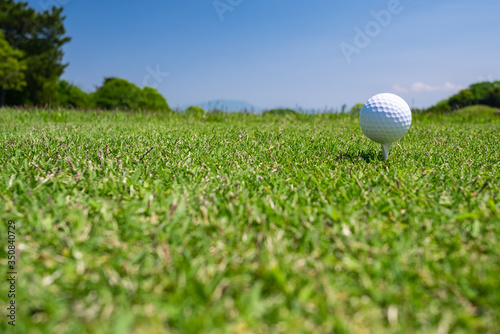 Golf Ball on tee at the teeing area. Golf course with a rich green turf beautiful scenery.