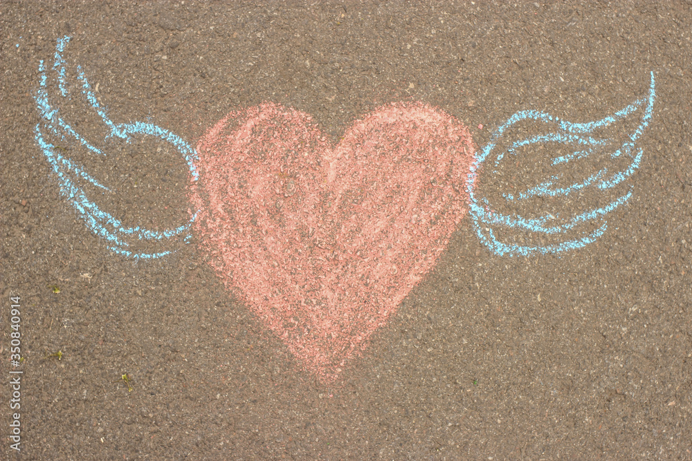 A heart with wings is drawn in red chalk on the asphalt A heart with wings is drawn in red chalk on the asphalt