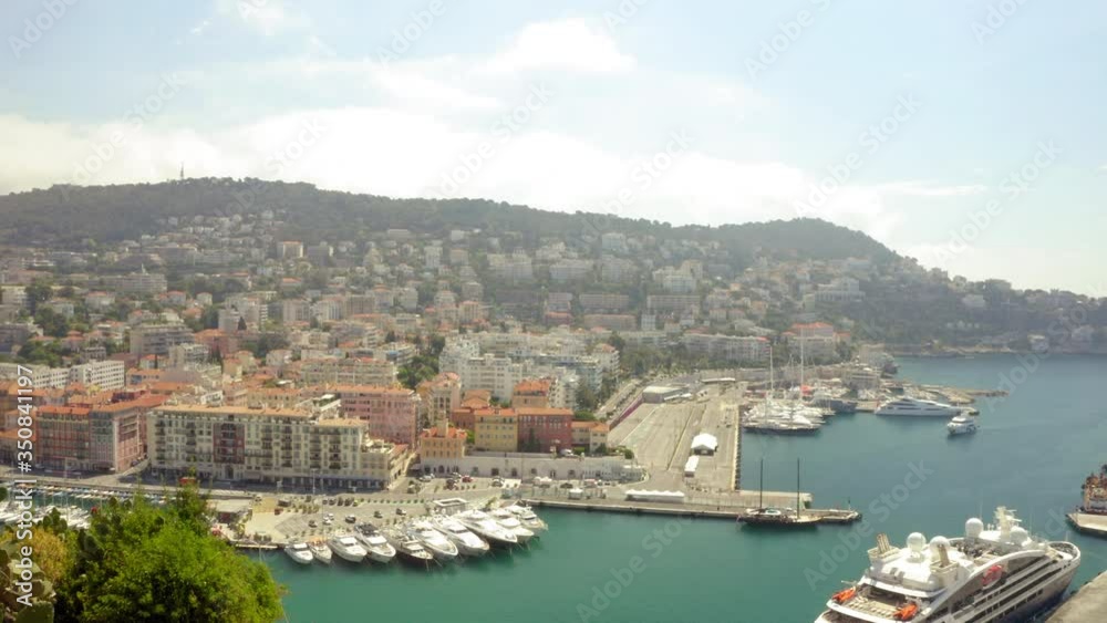Aerial shot of luxury nautical vessels moored at harbor in city, drone moving near cactus against sky on sunny day - Nice, France Aerial shot of luxury nautical vessels moored at harbor in city, drone moving near cactus against sky on sunny day - Nice, France