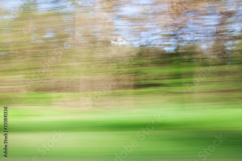 Defocused background of window view of moving car. Blurry image of grass, sky and trees