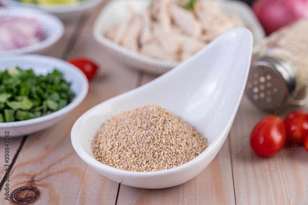 Roasted rice in a white spoon, tomato placed on a wooden table. Roasted rice in a white spoon, tomato placed on a wooden table.