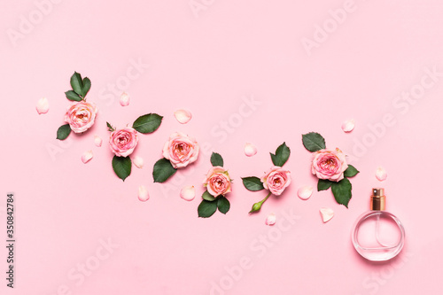 Fototapeta Naklejka Na Ścianę i Meble -  Women's perfume bottle and roses flowers on pink background. Minimal beauty concept, copy space