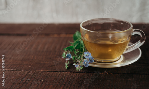 glass cup of tea with herbs. flowers in the cup.