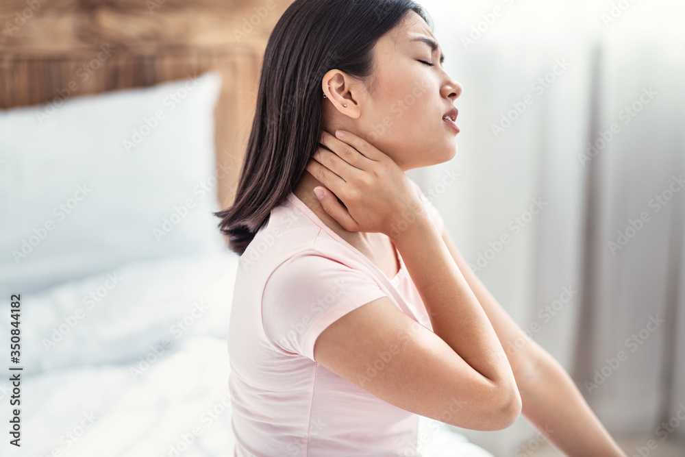 Korean Woman Having Neck Pain Sitting In Bed At Home Korean Woman Having Neck Pain Sitting In Bed At Home