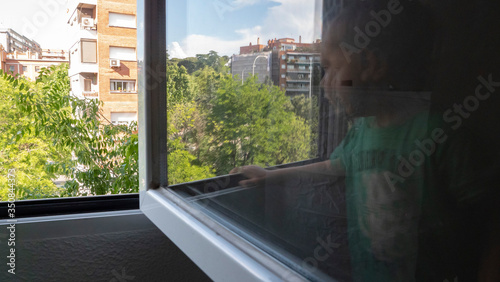 boy looking at the street through his window and his reflection in the glass photo