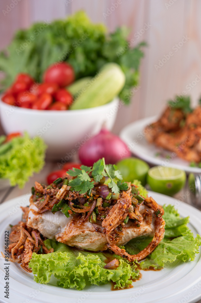 Spicy minced chicken on a white plate complete with cucumber, lettuce and side dishes. Spicy minced chicken on a white plate complete with cucumber, lettuce and side dishes.