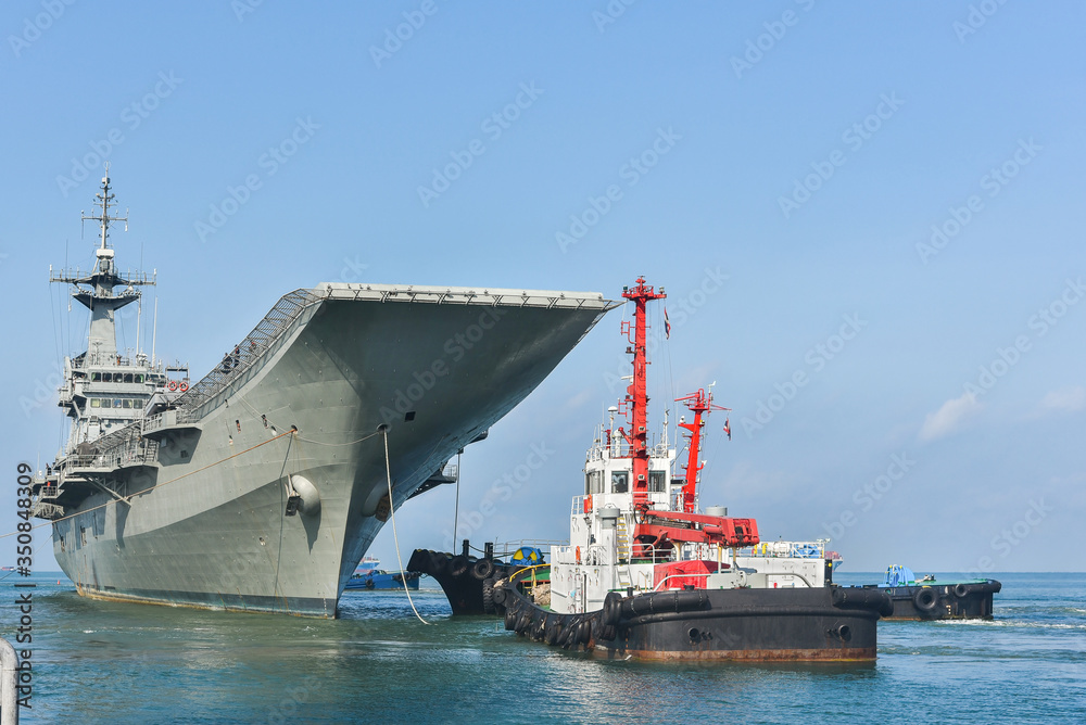 Fototapeta premium Front Old warships from war in shipyard Tug boat helps drag after maintenance and repairing compleated.