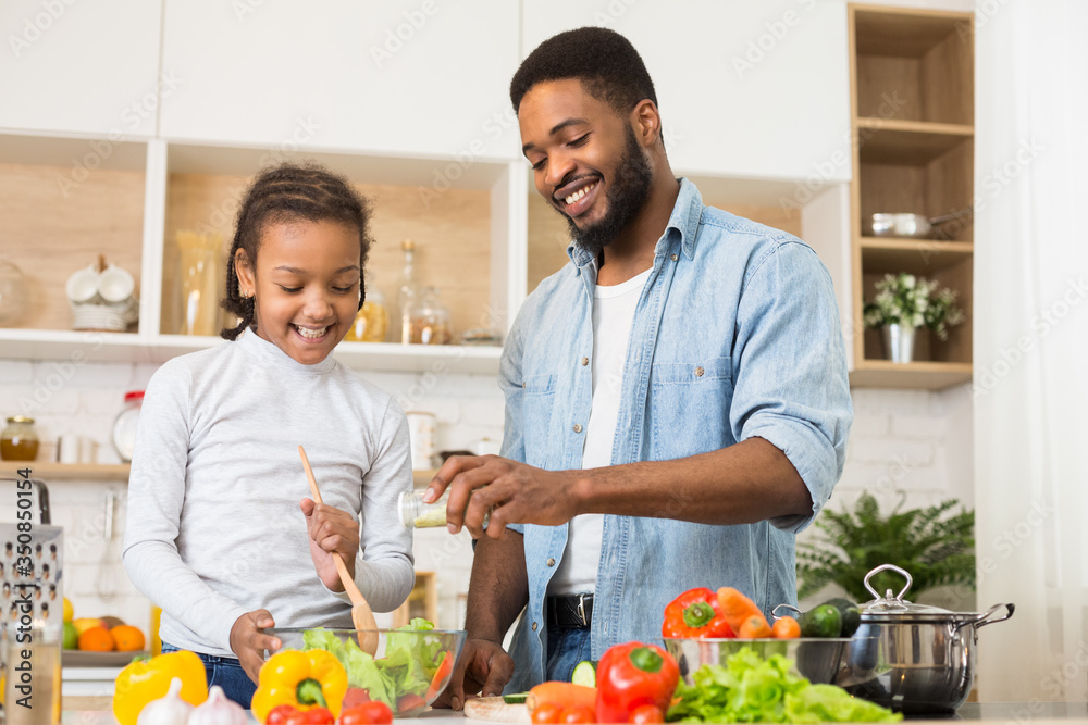Cheerful dad seasoning salad, cooking with daughter Cheerful dad seasoning salad, cooking with daughter
